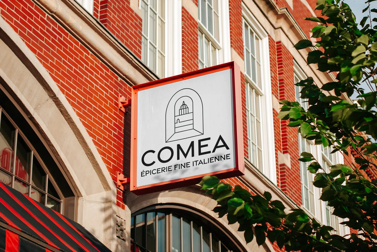 Enseigne COMEA installée sur la façade en brique d'un magasin